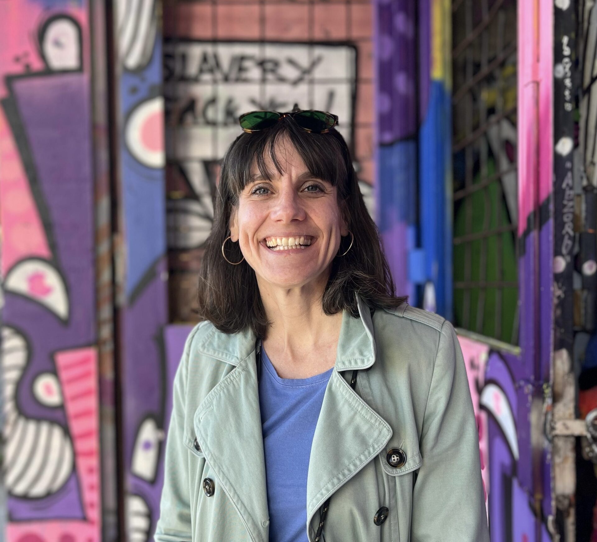 Anna Wolf – Anna Wolf, psychologische Beraterin und Karrierecoach in Berlin, vor bunter Graffiti‑Wand im mintgrünen Mantel und hellblauem Oberteil.